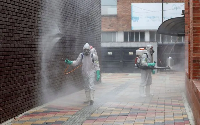 Worker in full protective gear amid the new coronavirus pandemic disinfect an alleyway at Corabastos, one of Latin America's largest food distribution centers, in Bogota, Colombia, Tuesday, June 23, 2020. The Corabastos general manager said that the market has workers controlling the temperature and applying disinfectant to those entering the place in an effort to curb the spread of COVID-19. (Photo by Fernando Vergara/AP Photo)