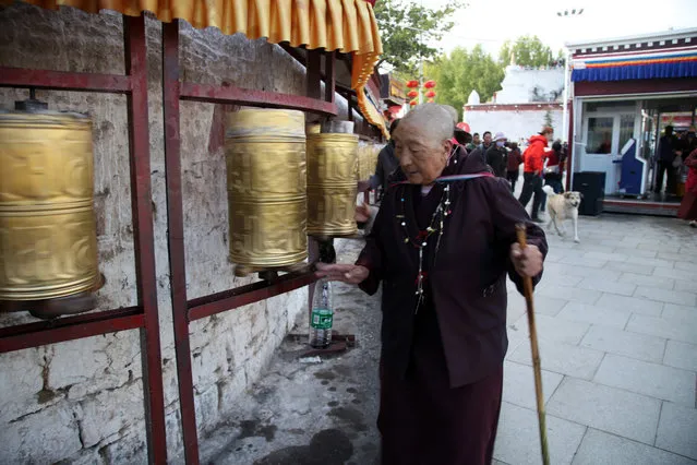 Tibetan Buddhist worshippers spin prayer wheels as they circumnavigate the Potala Palace in Lhasa, capital of the Tibet Autonomous Region in China, Saturday, September 19, 2015. (Photo by Aritz Parra/AP Photo)