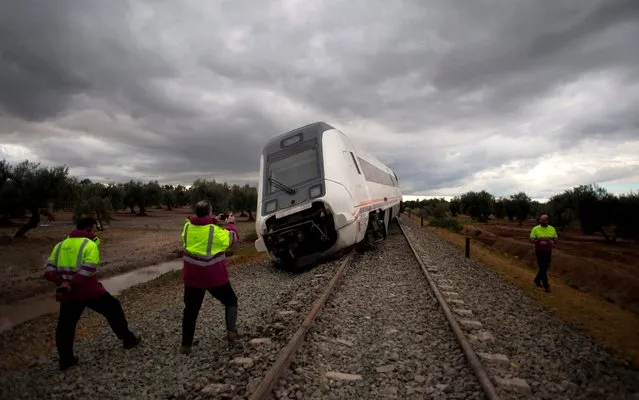Technicians of the Spanish state- owned rail company Renfe take pictures of a derailed train at Arahal, near Sevilla, on November, 29, 2017. A middle distance train travelling from Malaga to Seville with 79 passengers on board left 35 injured after derailing due to heavy rains. (Photo by Jorge Guerrero/AFP Photo)