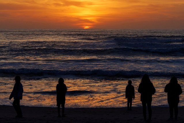 People gather to watch the sunset during low tide at Cardiff State Beach in Encinitas, California, on February 18, 2025. (Photo by Mike Blake/Reuters)