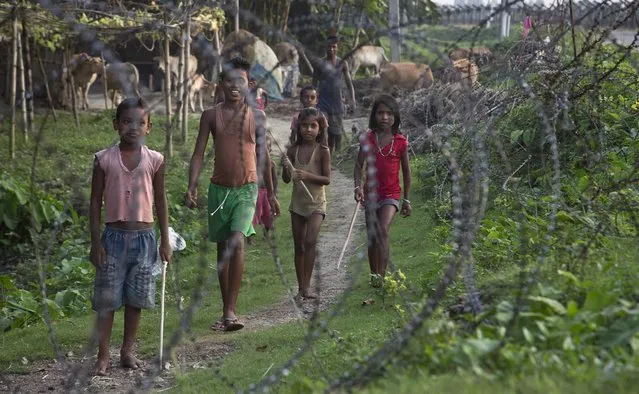 Indian children stand by a fence on the India-Bangladesh border at Jhalchar, in the northeastern Indian state of Assam, Friday, September 2, 2016. Chief Minister of Assam state Sarbananda Sonowal has sought help from the central government in sealing the porous border, one of the core issues of the ruling Bharatiya Janata Party's election campaign in Assam. (Photo by Anupam Nath/AP Photo)