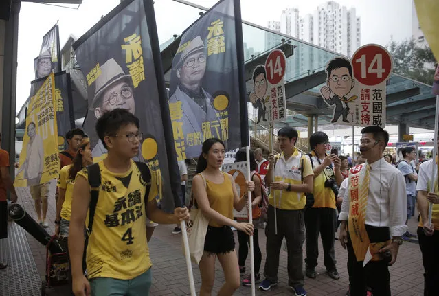 Radical activist candidate Gary Fan, right, looks at the supporters of Horace Chin, a radical activist candidate, during their election campaign in Hong Kong Saturday, September 3, 2016. Hong Kongers are heading to the polls Sunday in the first major election since 2014 pro-democracy street protests. A new crop of radical activists are challenging both pro-Beijing rivals and Hong Kong's mainstream pro-democracy parties for seats in the Legislative Council. A series of vandalized posters are a sign that the elections are the most contentious since the 1997 British handover of the city to China. At left is Hong Kong localist leader Edward Leung Tin-kei, one of the candidates rejected to participate in the Legislative Council elections. (Photo by Kin Cheung/AP Photo)