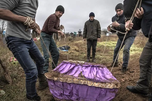 Local residents help police and war crimes investigators exhume the body of a 15-year-old girl, who local residents said had been executed by Russian forces along with several men whose bodies had been exhumed the day before, in the recently liberated village of Pravdyne, Ukraine on November 29, 2022. As days pass, the elation of the Kherson region’s liberation from Russian occupation has given way to mounting evidence of atrocities, and the sobering reality of battered, barely livable communities from which most civilians fled months ago and may not return anytime soon. (Photo by Finbarr O’Reilly/The New York Times)
