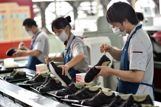 In this July 29, 2015 photo, workers assemble shoes in a shoe factory in Yongjia county in eastern China's Zhejiang province. The Caixin preliminary survey of factory purchasing managers released Wednesday, September 23, 2015, showed that Chinese manufacturing activity fell to its lowest level in over 6 years, in the latest sign of the deepening slowdown in the world's second biggest economy. (Photo by Chinatopix via AP Photo)