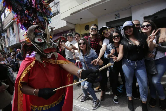Revelers watch as people dressed as devils parade past during the traditional New Year's festival known as “La Diablada”, in Pillaro, Ecuador, Friday, January 5, 2018. (Photo by Dolores Ochoa/AP Photo)