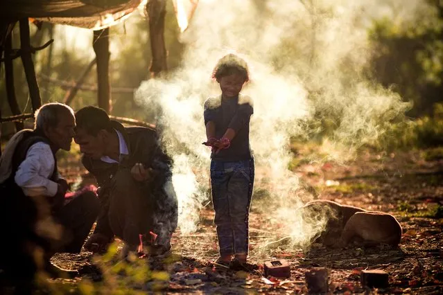 A child reacts to smoke from a bonfire lit by village elders to keep themselves warm on a wintry morning on the outskirts of Jabalpur on December 30, 2022. (Photo by Uma Shankar Mishra/AFP Photo)