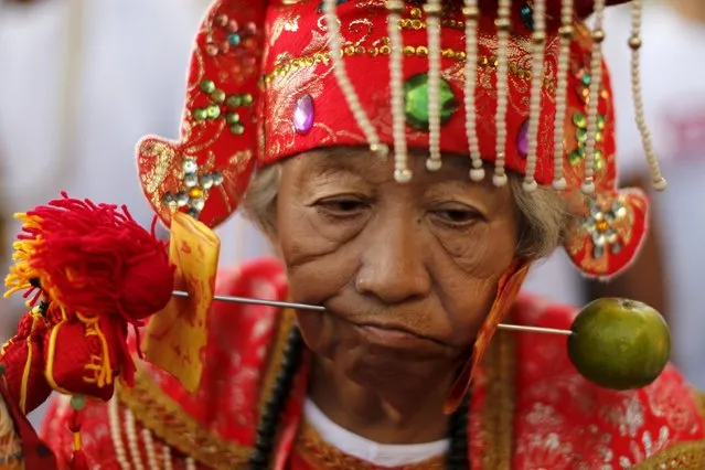 A devotee of the Chinese Jui Tui shrine walks with a spike pierced through her cheeks during a procession celebrating the annual vegetarian festival in Phuket, Thailand October 19, 2015. (Photo by Jorge Silva/Reuters)