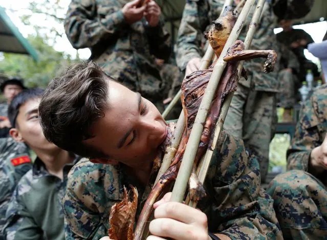 A US Marine tastes grilled monkey meat next to his South Korean comrades during jungle survival training as part of the multinational joint military exercise Cobra Gold 2018 at a Force Reconnaissance Battalion camp in the Royal Thai Naval Base, Sattahip district, Chonburi province, Thailand, 19 February 2018. (Photo by Rungroj Yongrit/EPA/EFE)