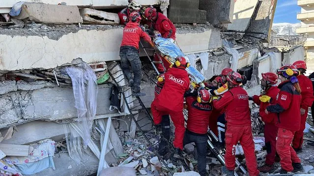 Rescuers carry a woman after she was evacuated from under a collapsed building following an earthquake in Kahramanmaras, Turkey on February 7, 2023. (Photo by Suhaib Salem/Reuters)