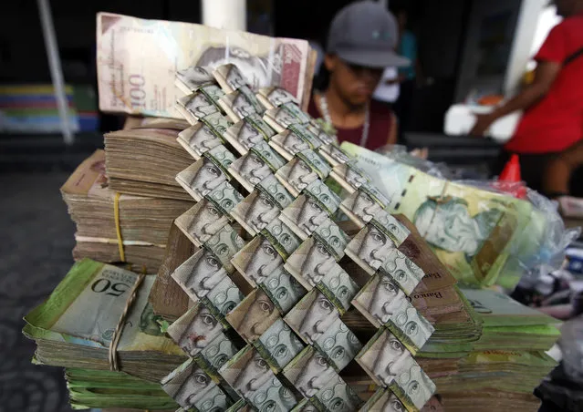 In this February 22, 2018 photo, Venezuelan Bolivars are weaved together at a vendor's table selling art and bags made from the currency in La Parada, Colombia, on the border with Venezuela. On a busy day, the creator Richard Segovia can sell as many as 20 items, and a bulk order recently came in from a woman who runs a boutique in Bogota who heard about his creations on local TV. (Photo by Fernando Vergara/AP Photo)