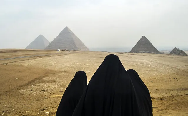 Women wearing veils look at the Great Pyramids of Giza as they stand from across the Giza plateau, on the southwestern outskirts of the Egyptian capital Cairo on February 15, 2018. (Photo by Khaled Desouki/AFP Photo)