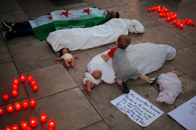 A child plays while Syrian refugee Hamad Othman, 21, lies on the ground covered with a Syrian opposition flag as he takes part in a protest against the war in Syria, during the International Day of Non-Violence, in Malaga, southern Spain, October 2, 2016. (Photo by Jon Nazca/Reuters)
