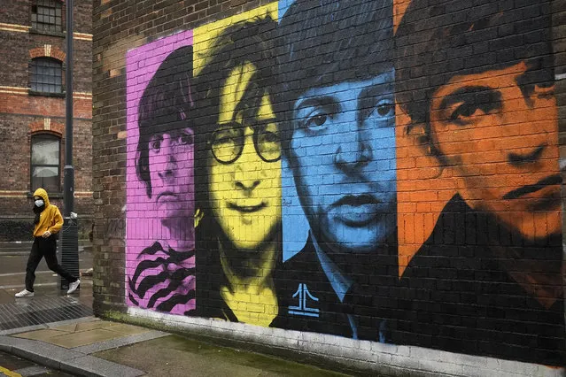 A woman wears a Covid-19 protective face mask as she walks past a mural of the Beatles on October 12, 2020 in Liverpool, England. Under a new three-tier system, English cities will be subject to lockdown measures corresponding with the severity of covid-19 outbreaks in their areas. (Photo by Christopher Furlong/Getty Images)