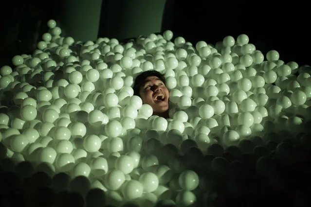 A man is partially submerged in an inflatable play station filled with plastic balls on Thursday, March 8, 2018, in Singapore. The Art-Zoo Inflatable Park is part of the i Light Marina Bay festival which showcases large scale creative installations within the urban city space. (Photo by Wong Maye-E/AP Photo)