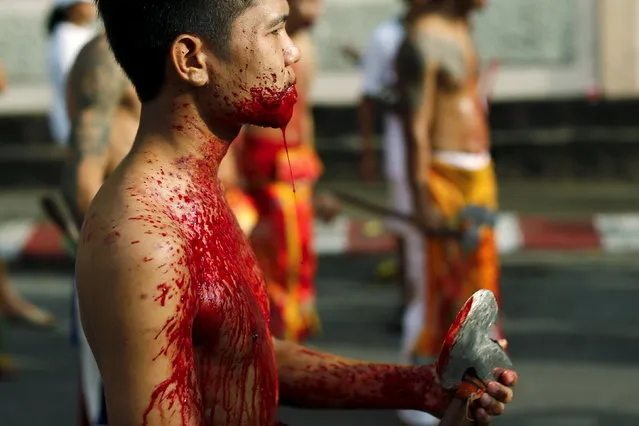 A devotee of the Chinese Samkong Shrine walks with a bleeding tongue after cutting it with an axe during a procession celebrating the annual vegetarian festival in Phuket, Thailand, October 16, 2015. The festival, featuring face-piercing, spirit mediums and strict vegetarianism celebrates the local Chinese community's belief that abstinence from meat and various stimulants during the ninth lunar month of the Chinese calendar will help them obtain good health and peace of mind. (Photo by Jorge Silva/Reuters)