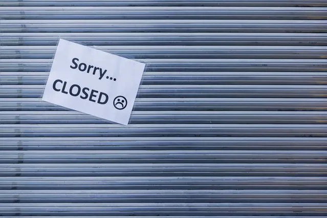 “Sorry Closed” is written on a piece of paper stuck to the lowered shutter of a closed snack bar in Muenster, Germany, Tuesday, November 3, 2020. A four-week partial lockdown has begun throughout Germany on 02.11.2020 to slow down the spread of the corona virus. (Photo by Rolf Vennenbernd/dpa via AP Photo)