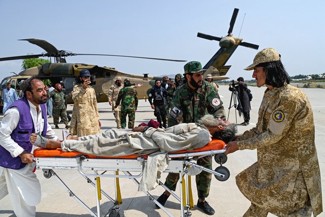 Afghan volunteers and Taliban security personnel carry an earthquake victim evacuated by a military helicopter from the Nurgal district of Kunar province, after his arrival for medical assistance in Jalalabad on September 1, 2025. A massive rescue operation was underway in Afghanistan on September 1, after a strong earthquake and multiple aftershocks flattened homes in a remote, mountainous region, killing more than 800 people, the Taliban authorities said. (Photo by Wakil Kohsar/AFP Photo)
