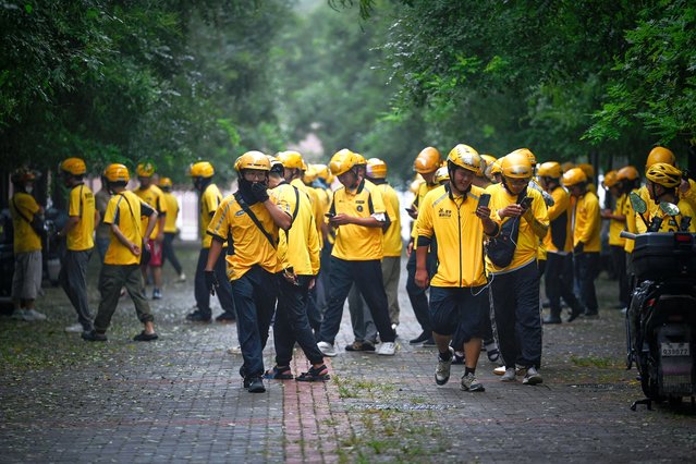 Deliverymen of Chinese shopping platform Meituan leave after a briefing before they start their shift near a mall in Beijing on August 21, 2025 (Photo by Wang Zhao/AFP Photo)