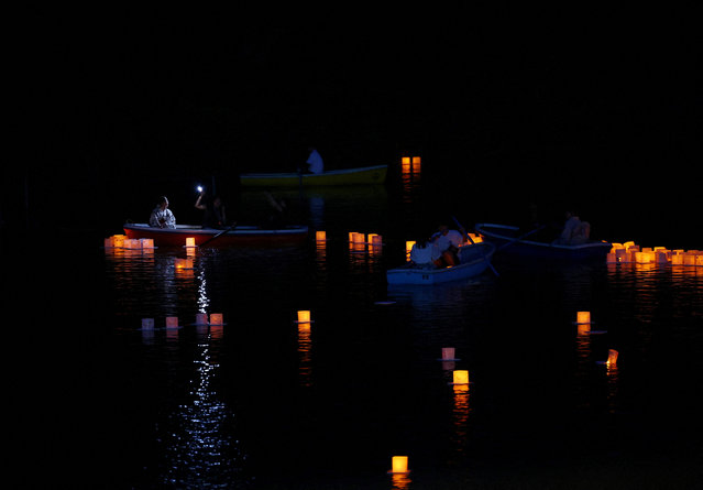 People sail boats around floating lanterns during the Lantern Floating Festival in Tokyo, Japan on July 31, 2025. About a thousand lanterns, inscribed with messages of gratitude, hope, and wishes, are released onto the water during the festival. (Photo by Kim Kyung-Hoon/Reuters)