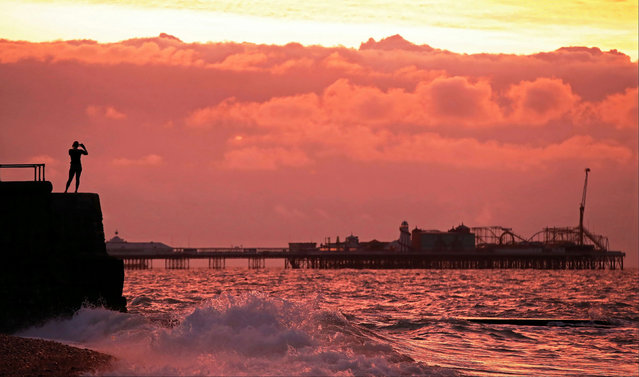A woman takes a photo of Brighton Palace Pier and the sunrise in Brighton, Britain, November 11, 2020. (Photo by Peter Cziborra/Reuters)