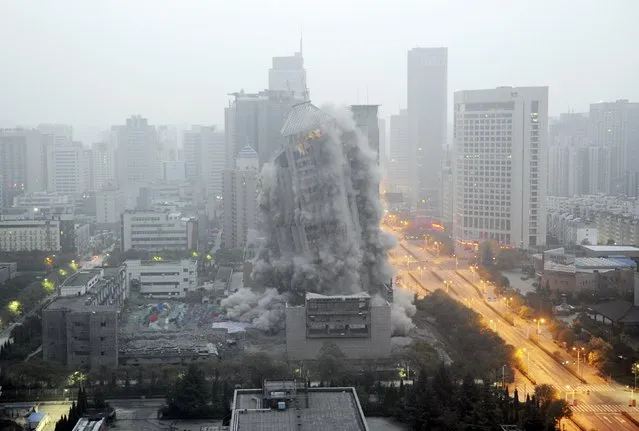 A building crumbles during a controlled demolition to make way for a new commercial centre in Xi'an, Shaanxi province, China, November 15, 2015. The 118-metre-tall building, which was taken down by 1.4 tonnes of explosives in Xi'an, was reported to be by far the tallest building in China being demolished by controlled explosion, local media reported. (Photo by Reuters/Stringer)