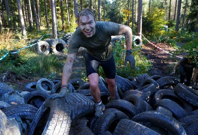 A competitor climbs over tyres during the Wildsau Dirt Run (Wild Boar Dirt Run) obstacle course fun race at Hellsklamm ravine in Obertriesting, Austria, October 22, 2016. (Photo by Heinz-Peter Bader/Reuters)