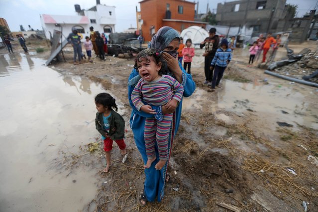 A Palestinian woman carries her crying daughter after rainwater flooded their house that witnesses said was damaged by Israeli shelling during the 50-day war in the summer of 2014,  in Khan Younis in the southern Gaza Strip October 7, 2015. (Photo by Ibraheem Abu Mustafa/Reuters)