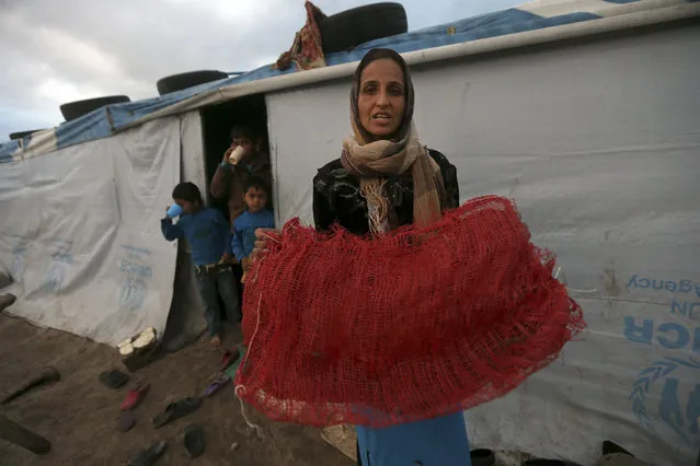 A Syrian refugee collects plastic bags to burn to warm her tent because she says she doesn't have money to buy wood or fuel at a Syrian refugee camp, in Deir Zannoun village, Bekaa valley, Lebanon, Monday, January 5, 2015. A snow storm is expected to hit Lebanon Monday affecting Syrian refugees, many of whom live in tents without proper heating. (Photo by Hussein Malla/AP Photo)