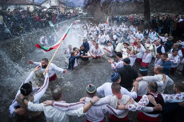 Bulgarian men perform the traditional “Horo” dance in the icy winter waters of the Tundzha river in the town of Kalofer, as part of Epiphany Day celebrations on January 6, 2021, despite the Covid-19 restrictions in the country. As a tradition, an Eastern Orthodox priest throws a cross in the river and it is believed that the one who retreives it will be healthy throughout the year as well as all those who dance in the icy waters. (Photo by Nikolay Doychinov/AFP Photo)