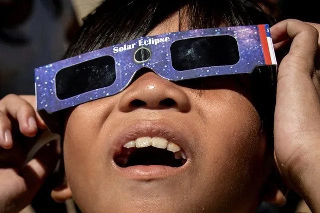 A boy looks at the hybrid solar eclipse with protective glasses, in Marikina City, Metro Manila, Philippines on April 20, 2023. (Photo by Eloisa Lopez/Reuters)
