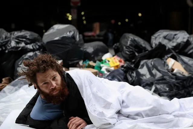 Alex, 27, who said he has been homeless for 8 years, lays on a sidewalk outside Port Authority bus station in the Midtown area of New York City, U.S., May 3, 2023. (Photo by Shannon Stapleton/Reuters)