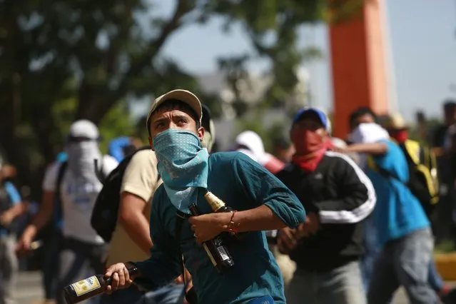 An activist throws bottles against the military police officers during a demonstration at the military zone of the 27th infantry battalion in Iguala, Guerrero, January 12, 2015. (Photo by Jorge Dan Lopez/Reuters)