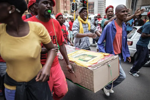 Protesters carry a cardboard mock up coffin with the picture of South African President Jacob Zuma as members and supporters of the South African opposition party, the Economic Freedom Fighters (EFF), demonstrate against South African president Jacob Zuma and in support of the release of the South African Public Protector “State Capture” report in Pretoria on November 2, 2016. South Africa' s anti- corruption watchdog on November 2 called for prosecutors to investigate alleged criminal activity as it released a report into President Jacob Zuma that fuelled further calls for him to resign. (Photo by Gianluigi Guercia/AFP Photo)