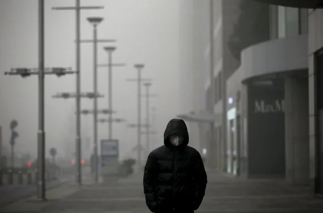 A man wearing a protective mask walks as smog covers China's capital Beijing on an extremely polluted day, December 1, 2015. (Photo by Jason Lee/Reuters)