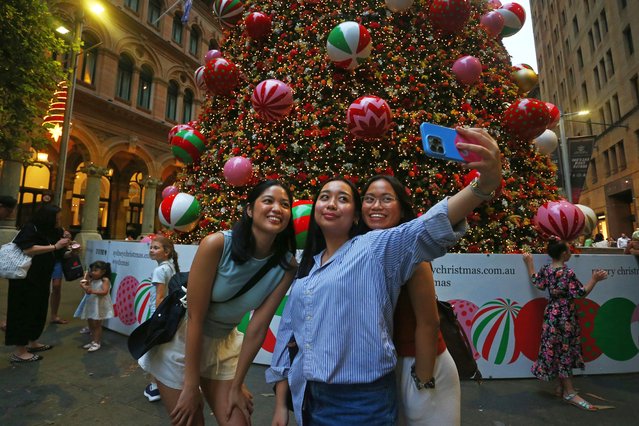 People take photographs in front of the Martin Place Christmas Tree on December 17, 2024 in Sydney, Australia. Each year Sydney's landmarks and streets are adorned with festive lights and projections for Christmas. (Photo by AFP Photo/Stringer)