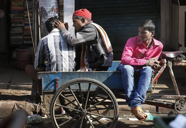 An Indian roadside traditional ear cleaner cleans the ear of a customer as other customer waits for his turn in New Delhi, India, 15 December 2015. There are hundreds of roadside traditional ear cleaners in India known as “Kaan- saaf-waalah” who engaged in this profession without any professional qualification. (Photo by Rajat Gupta/EPA)