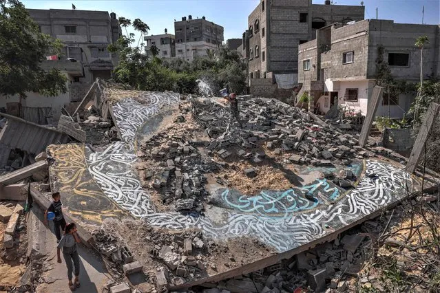 Palestinian artist Ayman Alhossary, 35, finalises Arabic calligraphy drawings on the remnants of a house destroyed by Israeli air strikes during the May 2023 conflict, in Beit Lahia in the northen Gaza Strip, on June 16, 2023. (Photo by Mohammed Abed/AFP Photo)