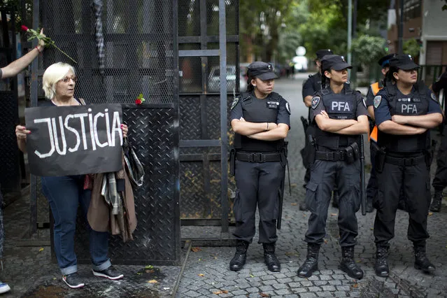 A woman holds a sign that reads in Spanish “Justice” by law enforcement officers standing guard near the funeral home where a private wake is held for prosecutor Alberto Nisman in Buenos Aires, Argentina, Wednesday, January 28, 2015. The prosecutor was scheduled to appear before congress the day after he was found dead in his apartment on Jan. 18, to detail his allegations that President Cristina Fernandez had conspired to protect some of the Iranian suspects in the 1994 bombing of a Jewish center. (Photo by Rodrigo Abd/AP Photo)