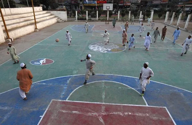 Madrasa (religious school) students play in a soccer match at a basketball court in Karachi's slum January 28, 2015. (Photo by Akhtar Soomro/Reuters)