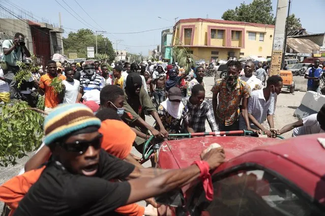 Protesters try to flip a car to block a street during a protest against insecurity in Port-au-Prince, Haiti, Monday, August 7, 2023. (Photo by Joseph Odelyn/AP Photo)
