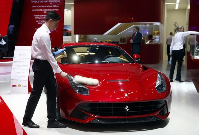 An employee dusts off a Ferrari F12berlinetta during the first press day ahead of the 85th International Motor Show in Geneva March 3, 2015. REUTERS/Arnd Wiegmann
