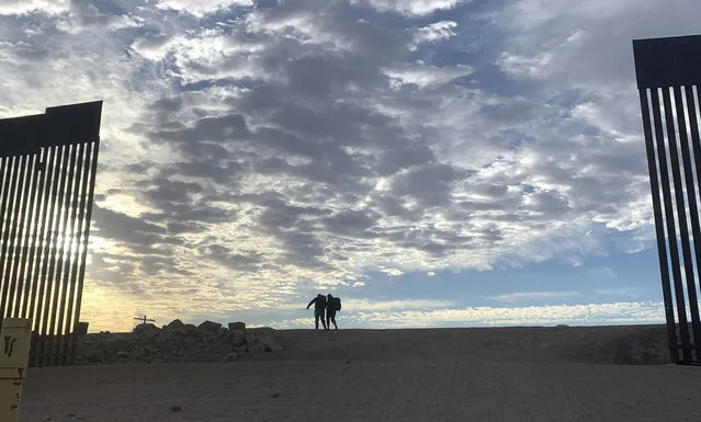 Cuban migrant Alain Rios, left, gets a helping hand from wife Katia Maden as they walk across the Mexico - U.S. border wall in Yuma, Ariz., Wednesday, June, 9, 2021 to seek asylum in the US. The pair mainly walked over four months from Venezuela before Rios sprained his ankle just steps away from reaching the US. The Biden administration says it has identified more than 3,900 children separated from their parents at the U.S.-Mexico border under former President Donald Trump's “zero-tolerance” policy on illegal crossings. The Border Patrol's Yuma, Arizona, sector recorded the highest number of separations of the agency's nine sectors on the Mexican border with 1,114. (Photo by Eugene Garcia/AP Photo)