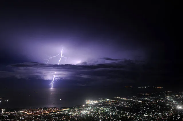 Lightning strikes over the sea along the coast of the Haitian capital, Port au Prince,  during an evening thunderstorm on September 24, 2014. (Photo by Hector Retamal/AFP Photo)