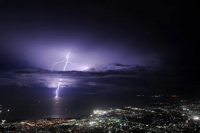 Lightning strikes over the sea along the coast of the Haitian capital, Port au Prince, during an evening thunderstorm on September 24, 2014. (Photo by Hector Retamal/AFP Photo)