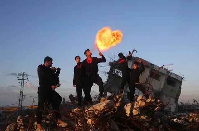 Palestinian youth, members of a Gazan martial art group, perform fire breathing at ruins of a house, that was destroyed in the 2014 war between Israel and Hamas militants, in Beit Hanoun in the northern Gaza Strip, on February  11, 2016. (Photo by Mohammed Abed/AFP Photo)
