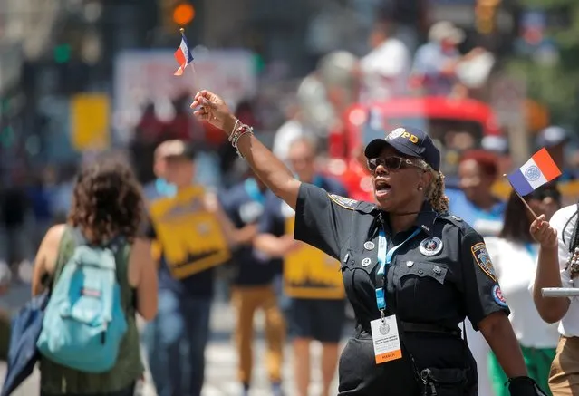 A police officer waves a small flag as she takes part in the Hometown Heroes ticker tape parade, to honor essential workers for their work during the outbreak of the coronavirus disease (COVID-19), up New York City's “Canyon of Heroes” in lower Manhattan in New York City, New York, U.S., July 7, 2021. (Photo by Brendan McDermid/Reuters)
