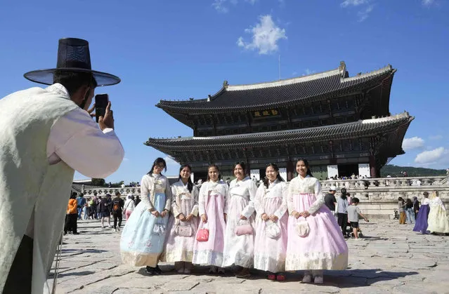 People wearing South Korean traditional “Hanbok” costume stand to take a picture as they visit to celebrate Chuseok holidays, the Korean version of Thanksgiving Day, at the Gyeongbok Palace in Seoul, South Korea, Sunday, October 1, 2023. (Photo by Ahn Young-joon/AP Photo)