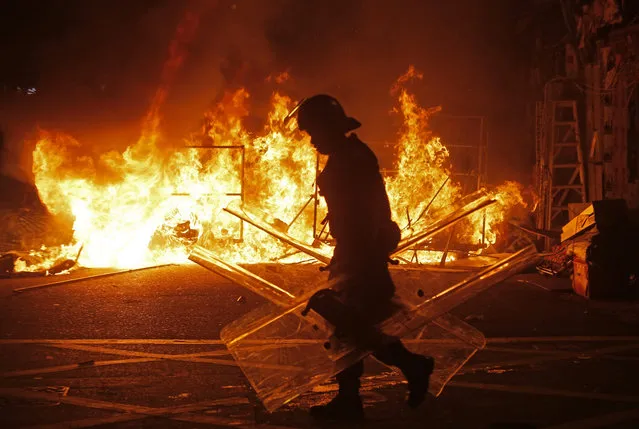 A police officer walks past fire set by rioters in Mong Kok district of Hong Kong, Tuesday, February 9, 2016. (Photo by Vincent Yu/AP Photo)