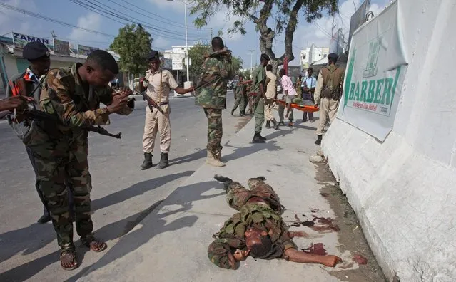 A Somali soldier photographs the body of one of the Al-Shabab militants as it lays on the ground outside the Maka Almukaramaha Hotel, in Mogadishu, Somalia, Saturday, March 28, 2015, who were killed during the second day of siege by Al-Shabab militants . Somali troops on Saturday took full control of a hotel that extremist gunmen stormed and occupied for more than 12 hours following a suicide bombing. (Photo by Farah Abdi Warsameh/AP Photo)