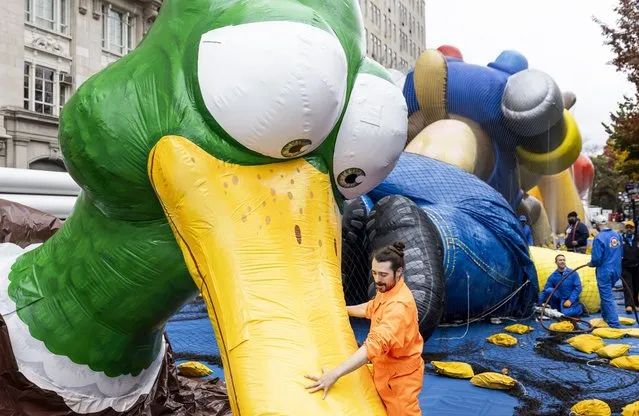 Workers inflate and secure giant helium balloons which will be a featured part of tomorrow's 97th annual Macy's Thanksgiving Day Parade in New York, New York, USA, 22 November 2023. The annual parade will feature 16 giant character helium balloons which will be lead down the street by teams of people. (Photo by Justin Lane/EPA)